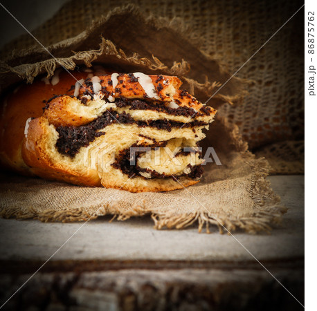 Fresh poppy seed roll on natural linen napkin on rustic wooden background Fresh poppy seed roll on natural linen napkin on rustic wooden background 86875762