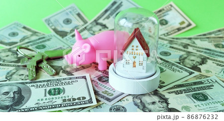 Piggy bank, toy house and keys on the background of dollar bills, the concept of material values, buying a house, developing finance 86876232