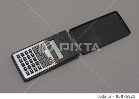 Scientific calculator against gray background. Rectangular device designed for engineering and scientific clock calculations. Selective focus. Scientific calculator against gray background. Rectangular device designed for engineering and scientific clock calculations. Selective focus. 86876929