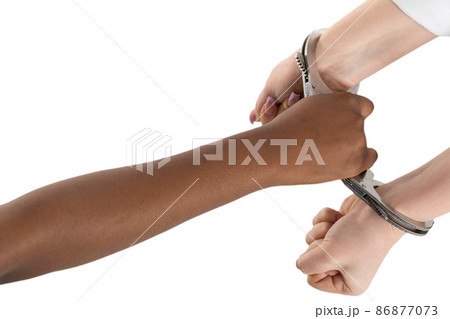 A clenched fist. Two female hands handcuffed. Two human races connected by steel handcuffs. Arrest of the guilty. A clenched fist. Two female hands handcuffed. Two human races connected by steel handcuffs. Arrest of the guilty. 86877073