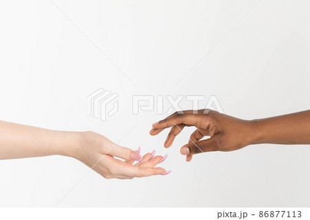 A helping hand outstretched to give support. Two hands approaching each other. Hands of two races, African and European, attracting each other. A helping hand outstretched to give support. Two hands approaching each other. Hands of two races, African and European, attracting each other. 86877113