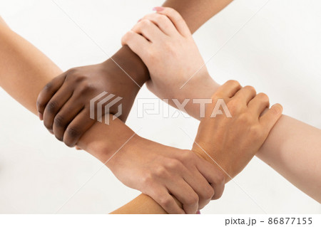 Each of the four hands is clasped around the friend's wrist. One hand grips the other, and so on. Young girl's hands. 86877155