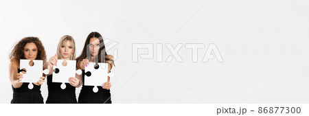A panoramic shot of three teenagers of different races holding puzzle pieces in their hands stretched far in front of them. Racial tolerance. 86877300