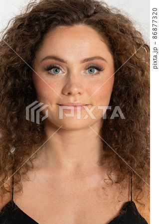 A girl with curly hair, fair skin and freckled skin. A joyful and smiling woman in the portrait photo. 86877320