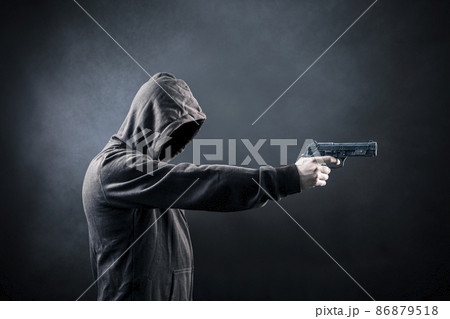 Hooded man with a gun in the dark 86879518