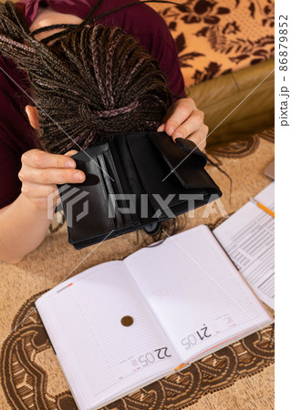 An adult teenager holds an empty wallet in her hands. Poor management of the household budget when one is very wasteful during everyday shopping. An adult teenager holds an empty wallet in her hands. Poor management of the household budget when one is very wasteful during everyday shopping. 86879852