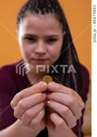 Teenagers were left with the last pennies of spending savings until the end of a long month. The girl holds a dime in her fingers, hoping for a better future 86879865