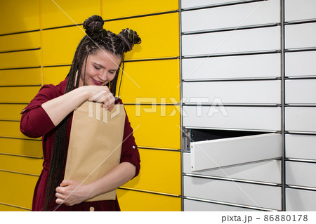 A young girl looks with interest and joy at the package that has just arrived. She received an unexpected mail. A young girl looks with interest and joy at the package that has just arrived. She received an unexpected mail. 86880178
