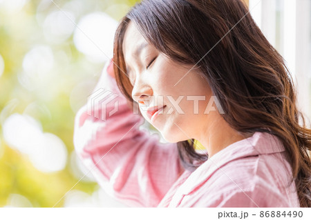 朝の光を浴びる部屋着を着た体調不調の女性 86884490