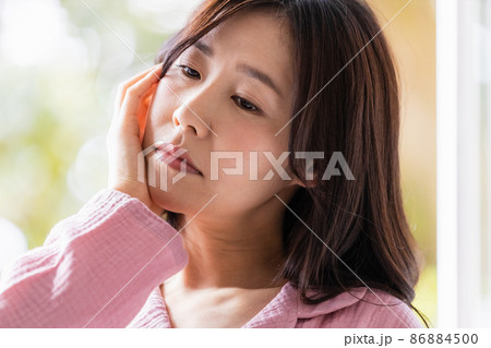 朝の光を浴びる部屋着を着た体調不調の女性 86884500