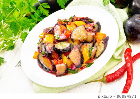 Eggplant with plums in plate on napkin Eggplant with plums in plate on napkin 86884871