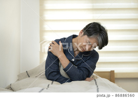 ベッドに座って肩を手で押える中高年男性 ベッドに座って肩を手で押える中高年男性 86886560