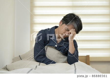 ベッドに座って頭を抱える50代の男性 ベッドに座って頭を抱える50代の男性 86886561