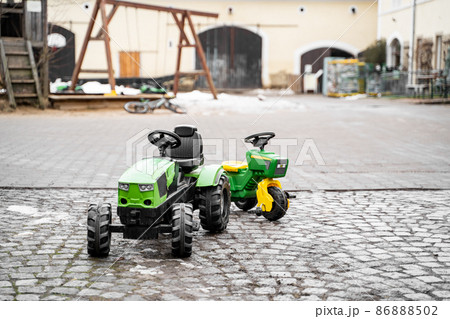 Green artificial tractor kids toy on farm or backyard at daytime on winter 86888502