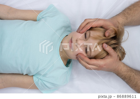 The osteopath works with the child's head. A teenage girl lies on a couch. The doctor gently palpates the head The osteopath works with the child's head. A teenage girl lies on a couch. The doctor gently palpates the head 86889611