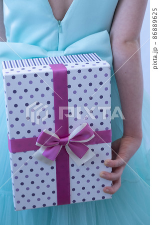 A teenage girl in an evening gown. The child holds the gift behind his back. Depersonalization A teenage girl in an evening gown. The child holds the gift behind his back. Depersonalization 86889625