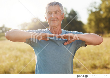 People, healthy lifestyle and pension concept. Satisfied refreshed grey haired senior man stretches hands, has outdoor training in morning, being active, cares of his body and being physically active 86890022