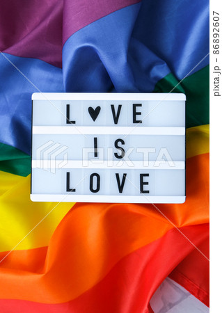 Rainbow flag with lightbox and text LOVE IS LOVE. Rainbow lgbtq flag made from silk material. Symbol of LGBTQ pride month. Equal rights. Peace and freedom Rainbow flag with lightbox and text LOVE IS LOVE. Rainbow lgbtq flag made from silk material. Symbol of LGBTQ pride month. Equal rights. Peace and freedom 86892607