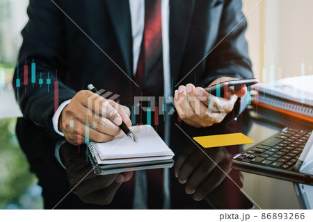 Male businessman use a take notes and laptop computer and in the notebook at the office desk in the morning. 86893266