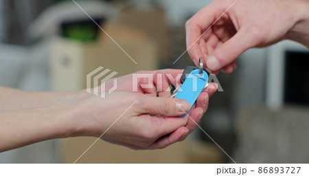 Close up of male hand passing key to female in new apartament. Man handing keys of new house to woman customer. Selling home. Real-estate agent job. 86893727