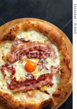 Carbonara pizza with bacon and egg on dark stone background Carbonara pizza with bacon and egg on dark stone background 86894291