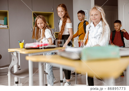 Happy schoolchildren with backpacks entering the classroom 86895773