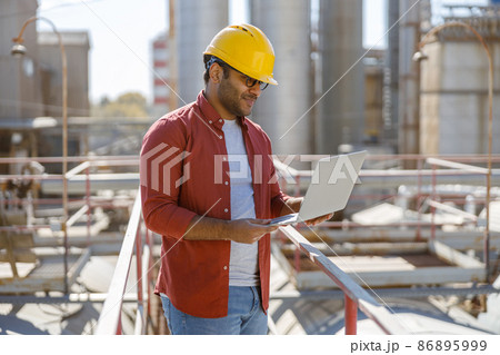 Young industrial engineer with using laptop at plant 86895999