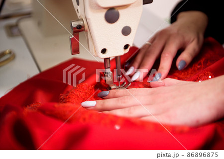 Seamstress is working sewing clothes in sewing machine, hands closeup. Seamstress is working sewing clothes in sewing machine, hands closeup. 86896875