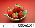 Red strawberries in a bowl. on red background 86896891