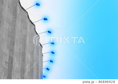 Concrete old building architecture structure cement facade apartment stone with elements of illumination bulbs on the roof against a background of sky Concrete old building architecture structure cement facade apartment stone with elements of illumination bulbs on the roof against a background of sky 86896928