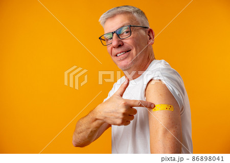 Senior man against yellow background recieved corona virus vaccination 86898041