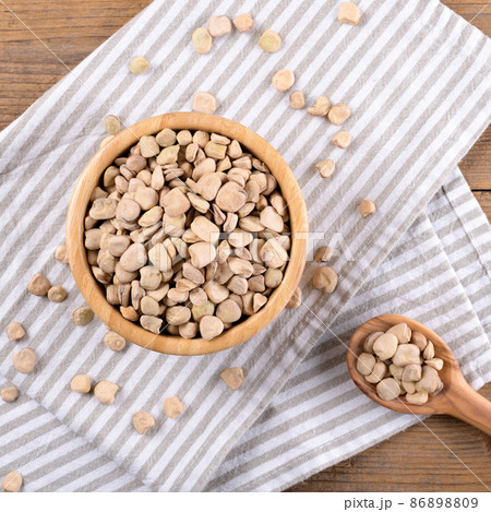 Cicerchia or indian pea on a wooden bowl with napkin on natural wooden background, gluten free food. Cicerchia or indian pea on a wooden bowl with napkin on natural wooden background, gluten free food. 86898809