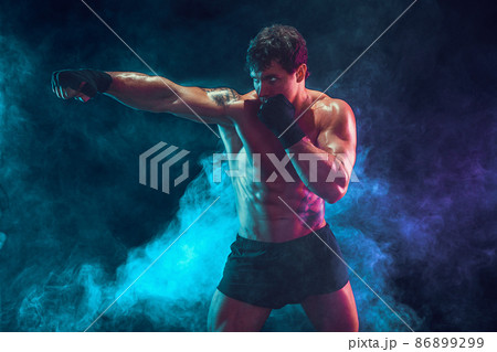 Half length of athlete boxer who training and practicing jab on smoke background. Sport concept Half length of athlete boxer who training and practicing jab on smoke background. Sport concept 86899299