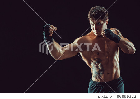 Portrait of aggressive boxer who training and practicing uppercut on black background. Sport concept 86899322
