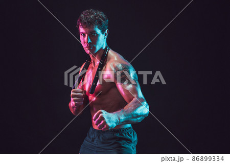 Studio shot of Strong male athlete who posing with nunchaku on black background. Sport concept Studio shot of Strong male athlete who posing with nunchaku on black background. Sport concept 86899334
