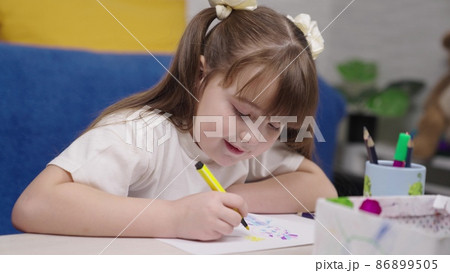 a small child draws with a felt-tip pen in an album, drawing lessons, kid in children's room plays an artist, a childhood dream to learn how to beautifully convey an image, girl paints color drawing 86899505