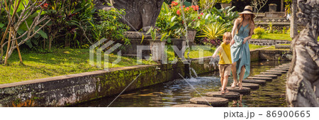 Mom and son tourists in Taman Tirtagangga, Water palace, Water park, Bali Indonesia. Traveling with children concept. Kids friendly place BANNER, LONG FORMAT 86900665