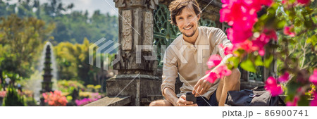 Young man tourist in Taman Tirtagangga, Water palace, Water park, Bali Indonesia BANNER, LONG FORMAT 86900741
