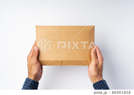 Male hand holding parcel post against white background Male hand holding parcel post against white background 86901858