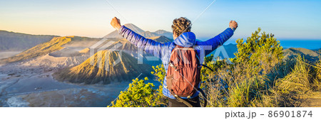 BANNER, LONG FORMAT Young man meets the sunrise at the Bromo Tengger Semeru National Park on the Java Island, Indonesia. He enjoys magnificent view on the Bromo or Gunung Bromo on Indonesian, Semeru 86901874