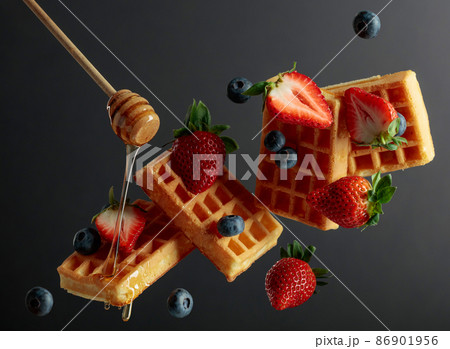 Waffles with blueberries, strawberries, and honey. Waffles with blueberries, strawberries, and honey. 86901956