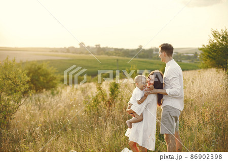 Mother, father and son in white clothes walking on the field 86902398