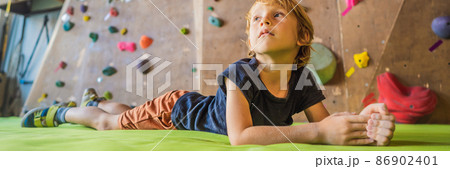 Boy resting after climbing a rock wall indoor BANNER, LONG FORMAT Boy resting after climbing a rock wall indoor BANNER, LONG FORMAT 86902401