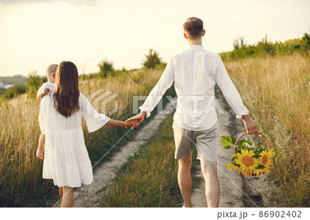 Back side photo of mother, father and son in white clothes walking on the field 86902402