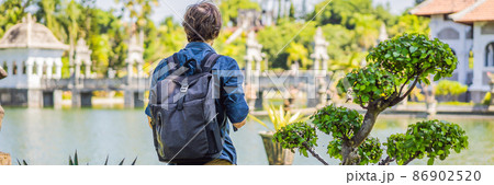 Young man in Water Palace Soekasada Taman Ujung Ruins on Bali Island in Indonesia. Amazing old architecture. Travel and holidays background BANNER, LONG FORMAT 86902520