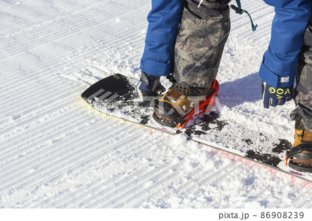 スノーボードのバインディングをつける男性の手元 86908239