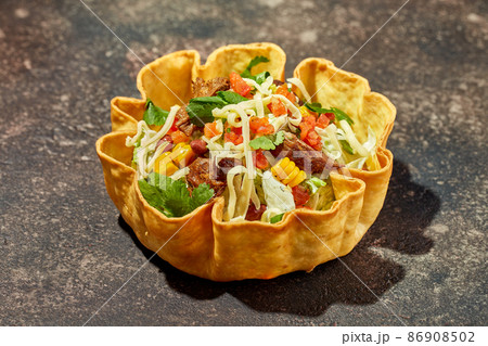 Taco salad in tortilla bowl with beef, cheese, corn and lettuce Taco salad in tortilla bowl with beef, cheese, corn and lettuce 86908502