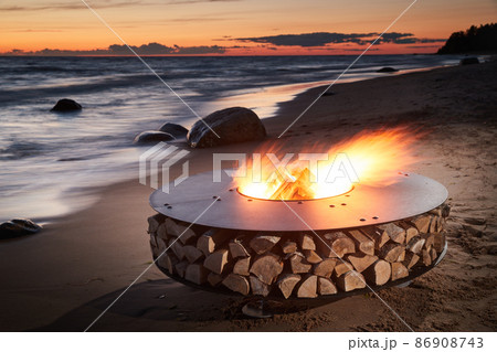 The beautiful metal round a fireplace stands on the sandy coast with a tidal wave at sunset, stones, sand, waves, the landscape, tranquillity, the sun falls, firewood, nobody The beautiful metal round a fireplace stands on the sandy coast with a tidal wave at sunset, stones, sand, waves, the landscape, tranquillity, the sun falls, firewood, nobody 86908743