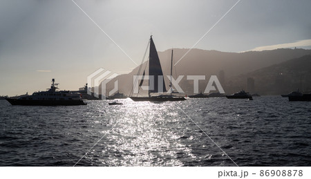 A lot of huge sail yachts and motor boats in port of Monaco at sunset, mountains are on background, megayachts are moored in sea, sun reflection on water, backlight A lot of huge sail yachts and motor boats in port of Monaco at sunset, mountains are on background, megayachts are moored in sea, sun reflection on water, backlight 86908878