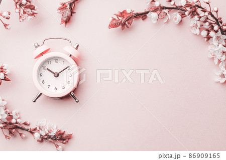 Spring time flowers blossom and may flowers with alarm clock on pink. For banner, branches of blossoming cherry against background. Dreamy romantic image, landscape panorama, copy space. 86909165